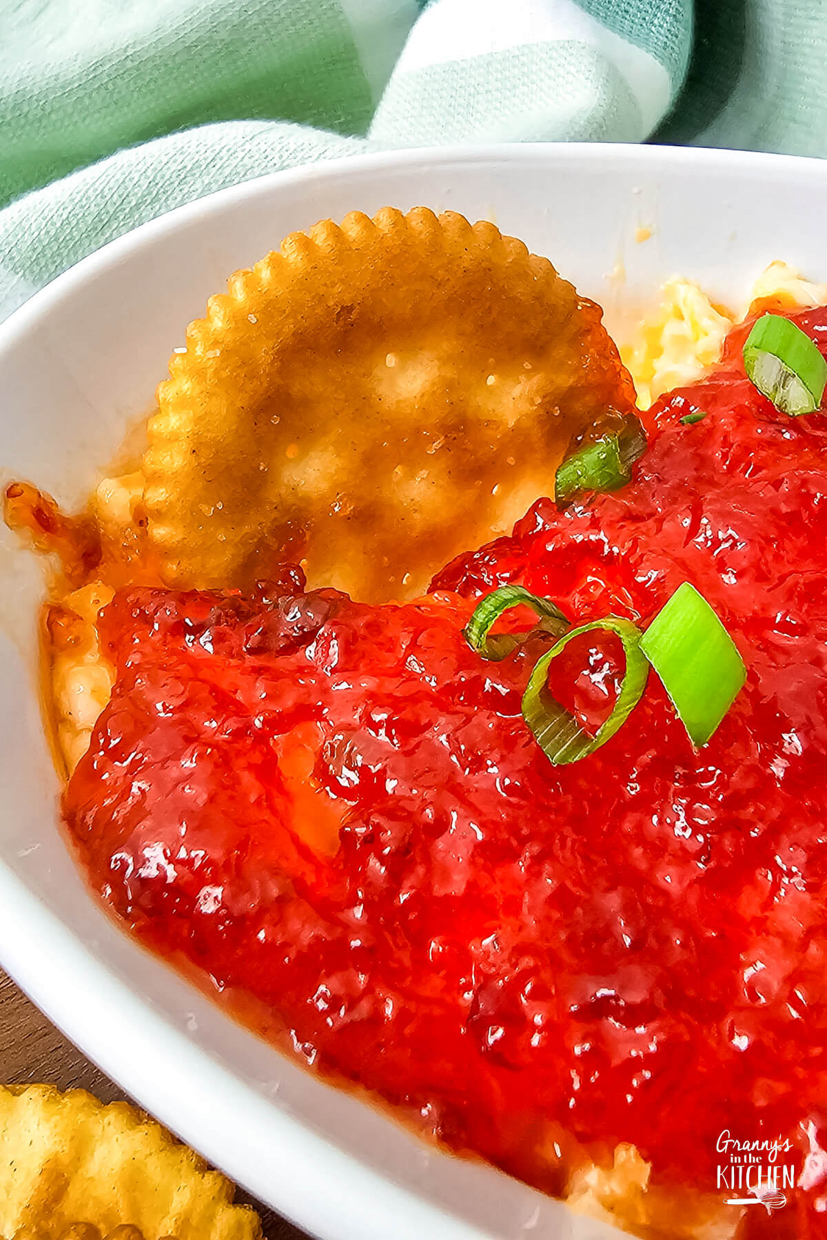 Red pepper cream cheese dip with a cracker dipping into it