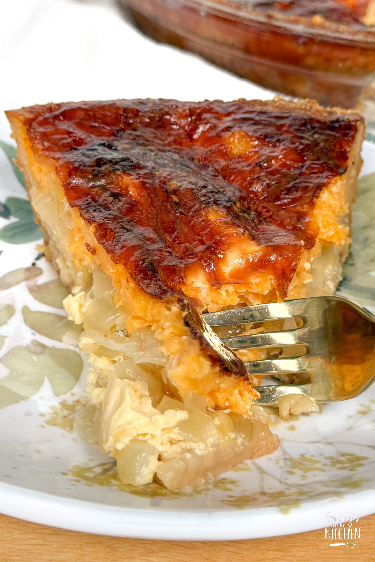 cutting into a piece of onion pie with a fork.