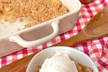 apple crisp in bowl with ice cream and in the pan, with text overlay of recipe name.