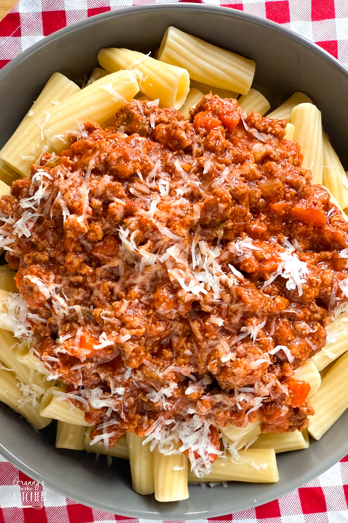 top down view of a bowl of rigatoni pasta topped with meat sauce.
