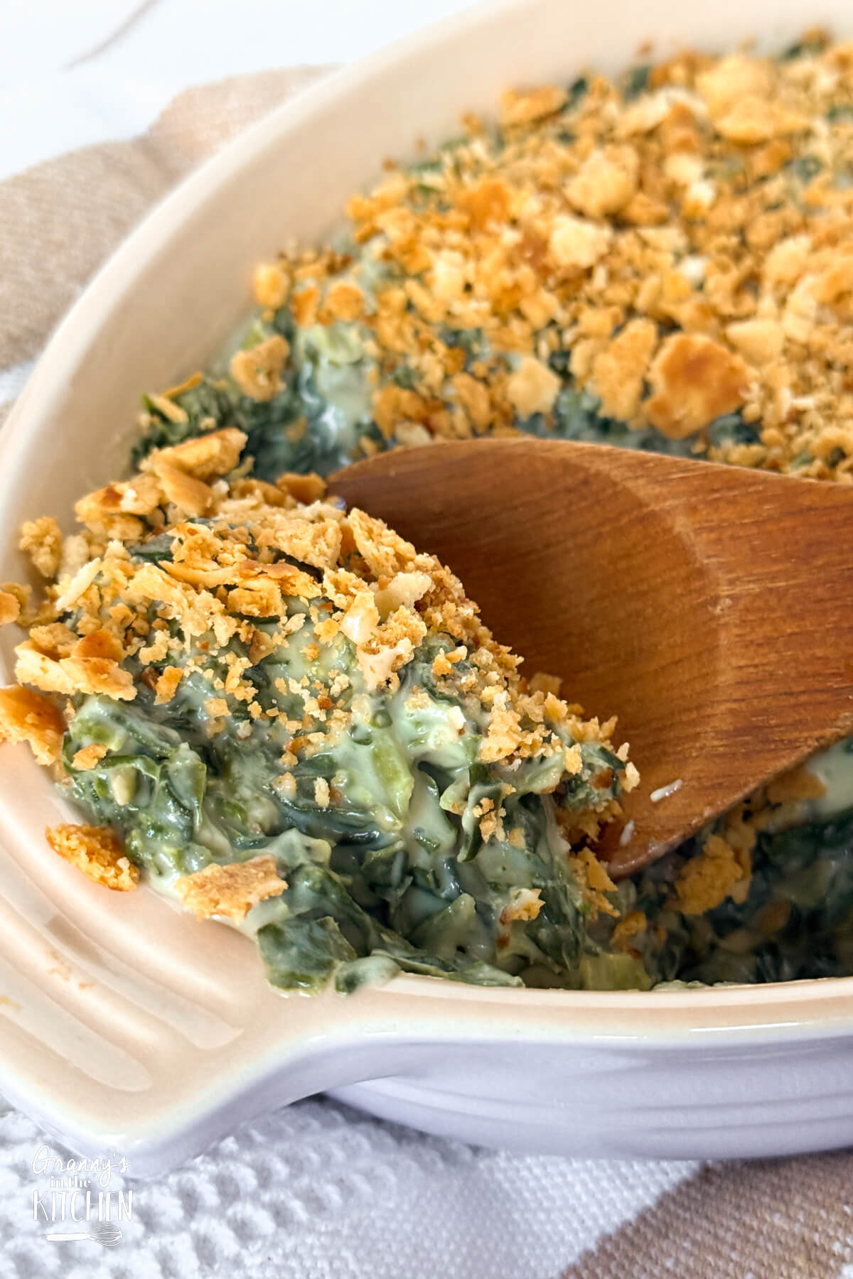scooping a serving of Spinach Madeline casserole out of the dish.