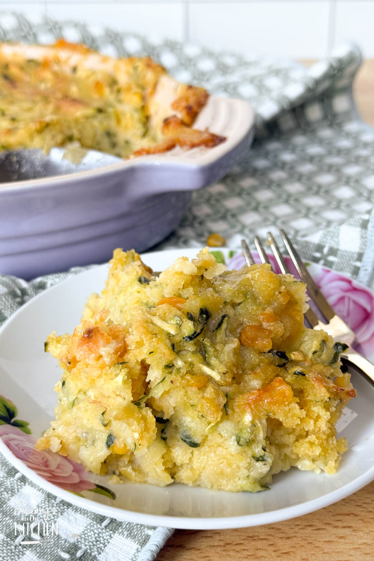 zucchini and corn casserole on a plate and serving dish in background.