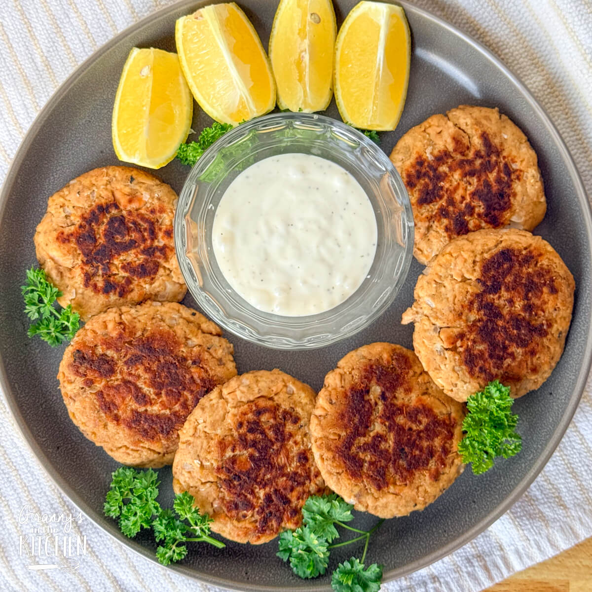 a round plate with fried salmon patties arranged in a circle.
