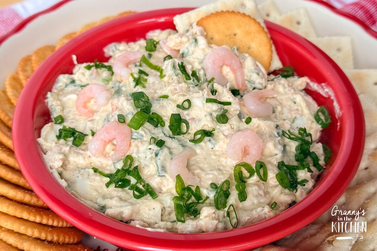 A red bowl of Shrimp Dip served with crackers.