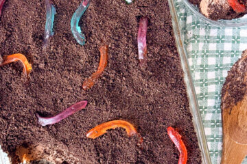 Dirt cake in a glass serving dish with one scoop taken out.