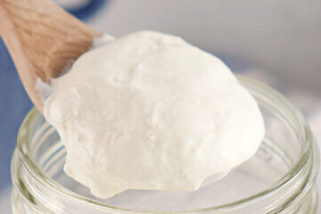 Homemade Sour Cream being spooned out of a jar.