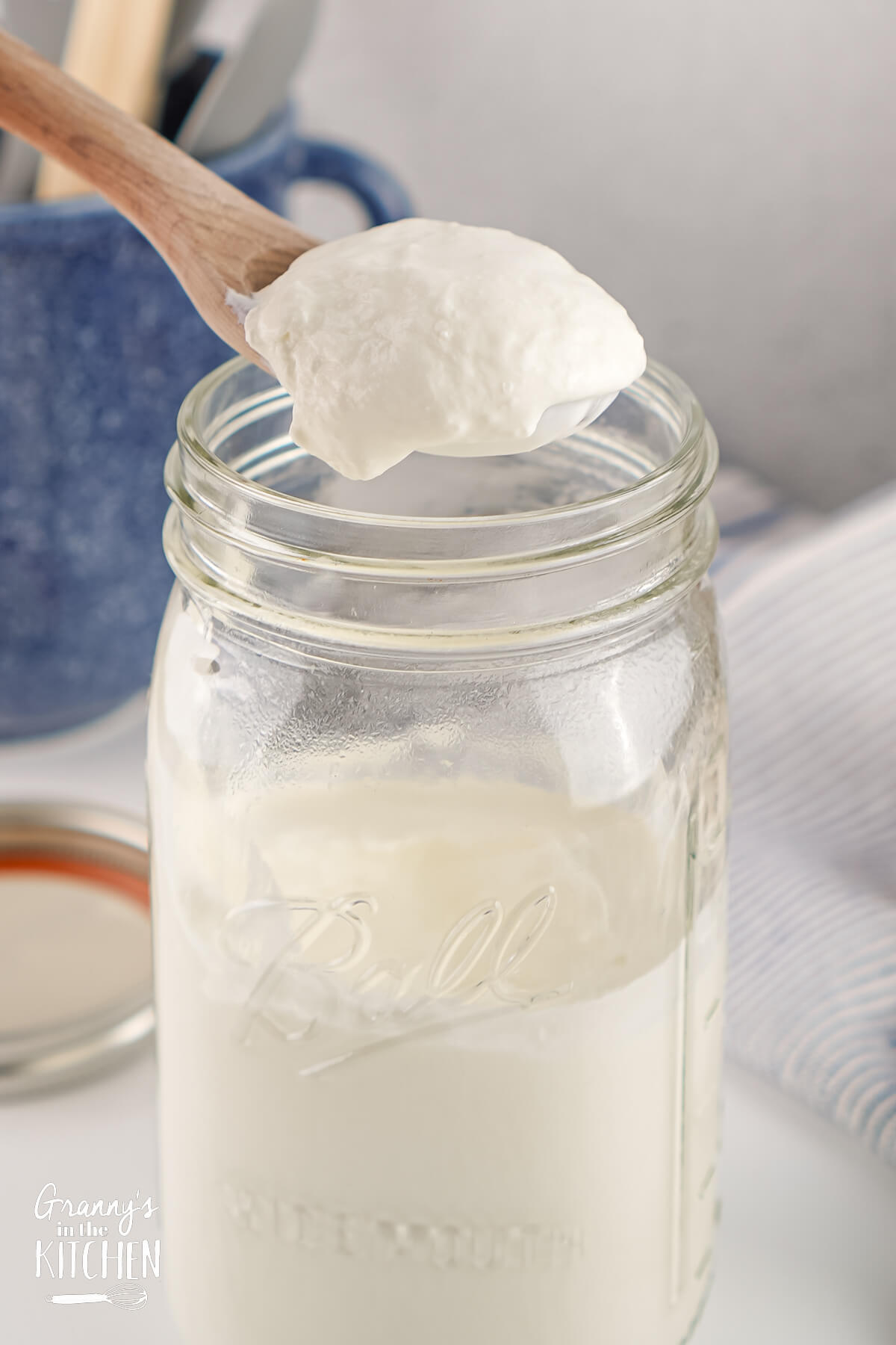 Sour Cream being spooned out of a glass mason jar.