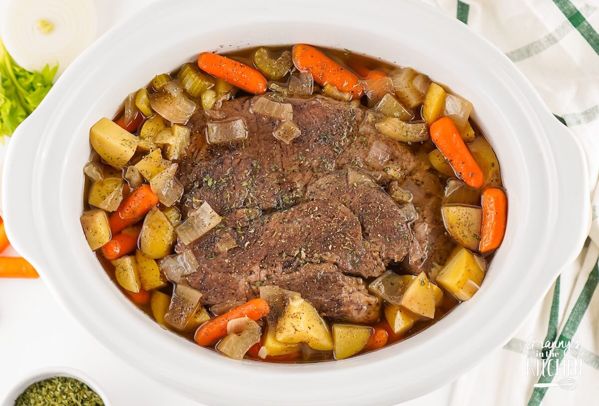 Pot roast in a white slow cooker.