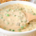 a bowl of peas in a thick and creamy cheese sauce; text overlay "Cheesy Peas."
