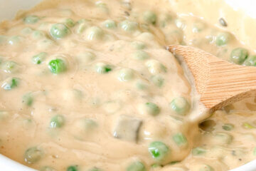 a bowl of peas in a thick and creamy cheese sauce; text overlay "Cheesy Peas."