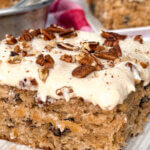 close up on the corner of a slice of brown sheet cake with cream cheese frosting.