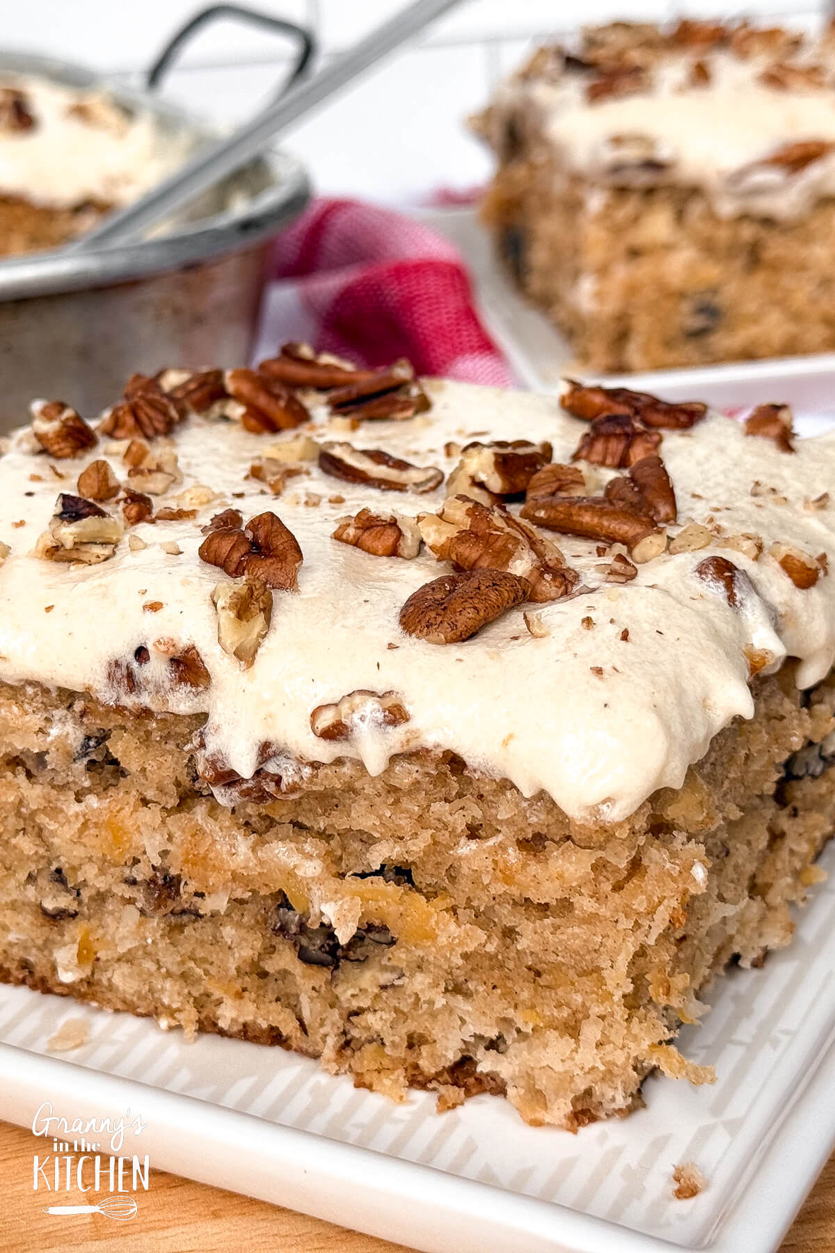 close up on the corner of a slice of brown sheet cake with cream cheese frosting.