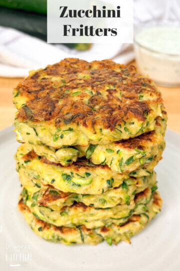stack of fried zucchini patties with text overlay "Zucchini Fritters"