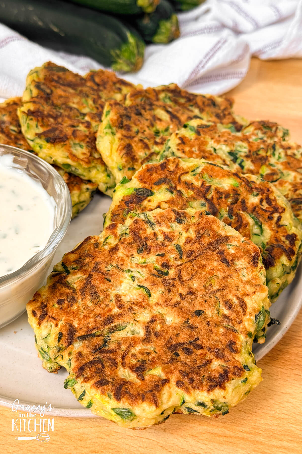 plate of pan fried zucchini fritters with ranch dressing.