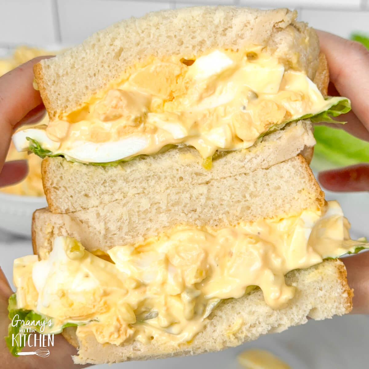 holding and egg salad sandwich.