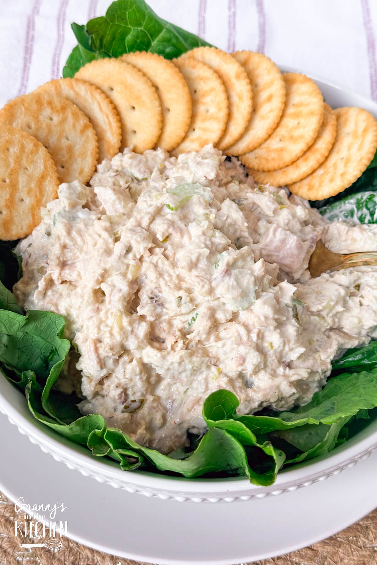 a bowl of homemade tuna salad on a bed of lettuce with crackers.