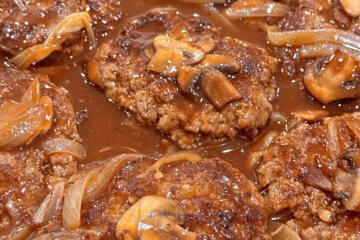skillet with homemade hamburger steak and gravy; text overlay "Classic Salisbury Steak"