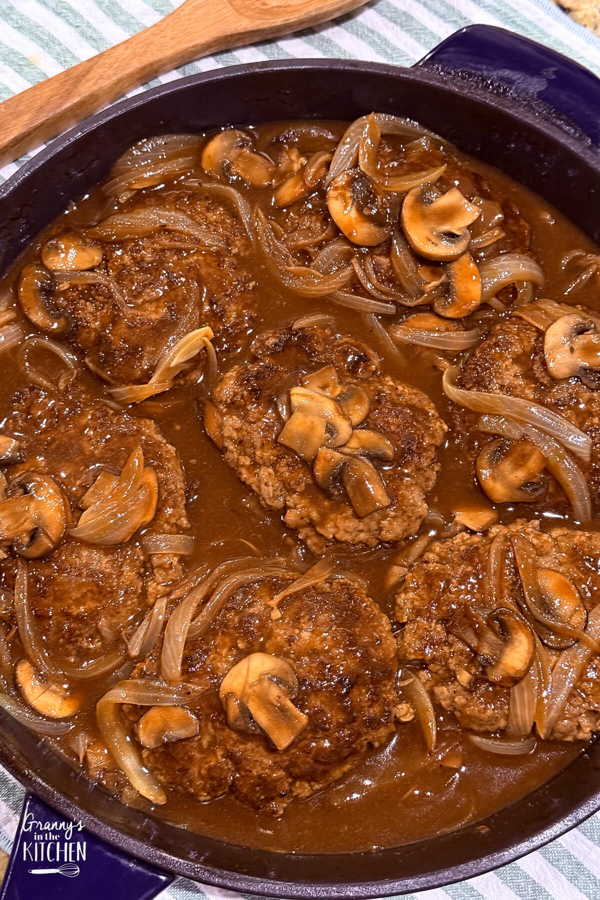 top down view of skillet containing salisbury steak patties with mushroom and onion gravy.