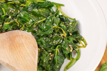 A white plate of Sautéed Spinach with a text overlay that says Classic Sautéed Spinach.