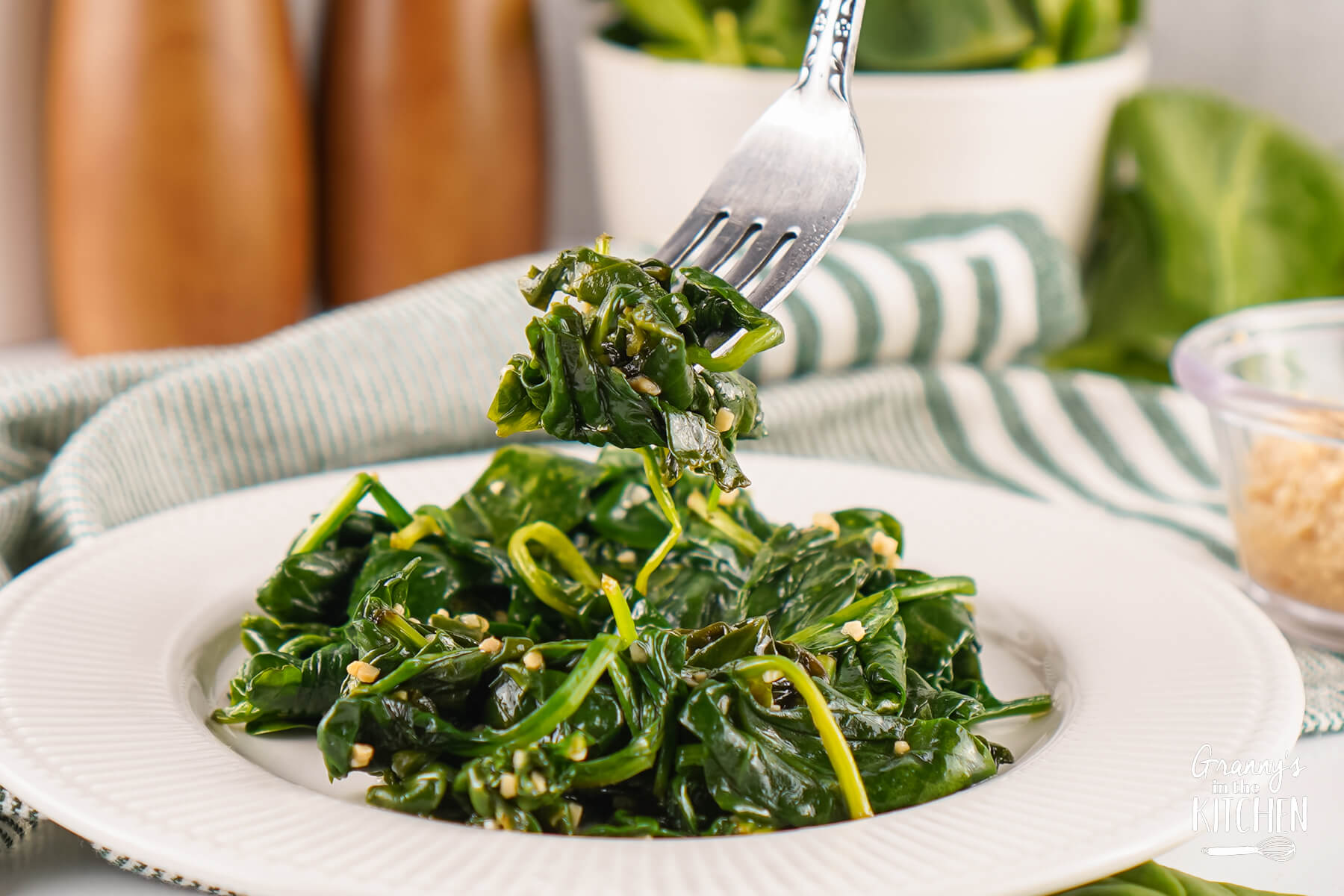 A fork full of Sautéed Spinach being lifted off a plate.