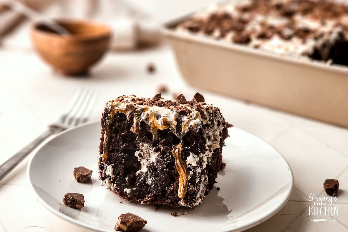 A slice of Toffee Poke Cake on a white plate.
